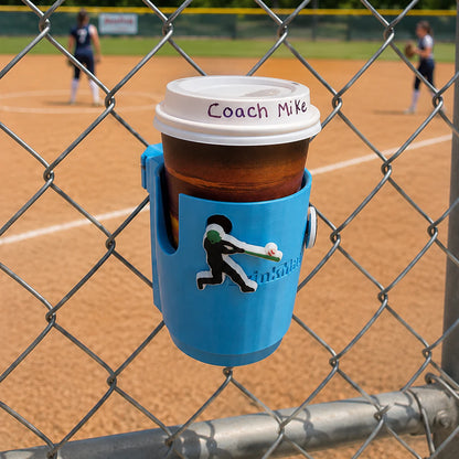 Drink Mate in light blue mounted on a fence holding a coffee cup with Crocs Jibbitz attached.