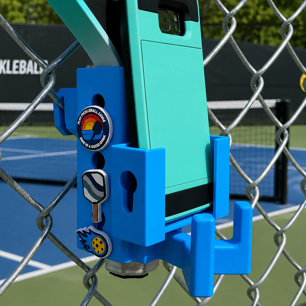 Paddle Mate in white mounted on a fence with Crocs Jibbitz charms, phone caddy attachment and eyeglasses ring attached.